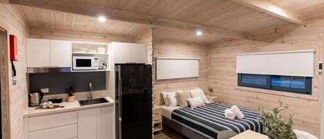 A compact room with a kitchenette, a bed, a small table, and a window.