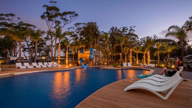 Una piscina con sillas de descanso y un tobogán de agua.