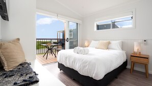 Un dormitorio con una cama grande, una mesita y un balcón con vistas.