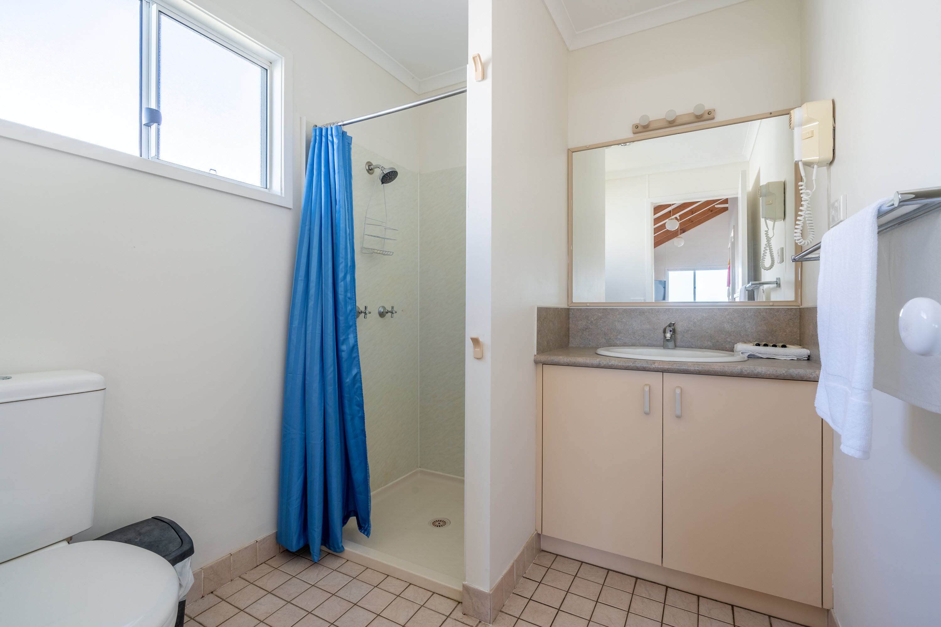A bathroom with a shower, toilet, sink, and mirror.