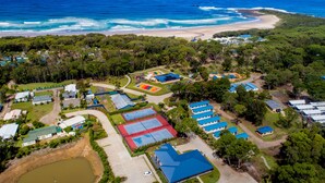 Vista aérea de un complejo turístico con varias construcciones, una playa y una gran extensión de agua.