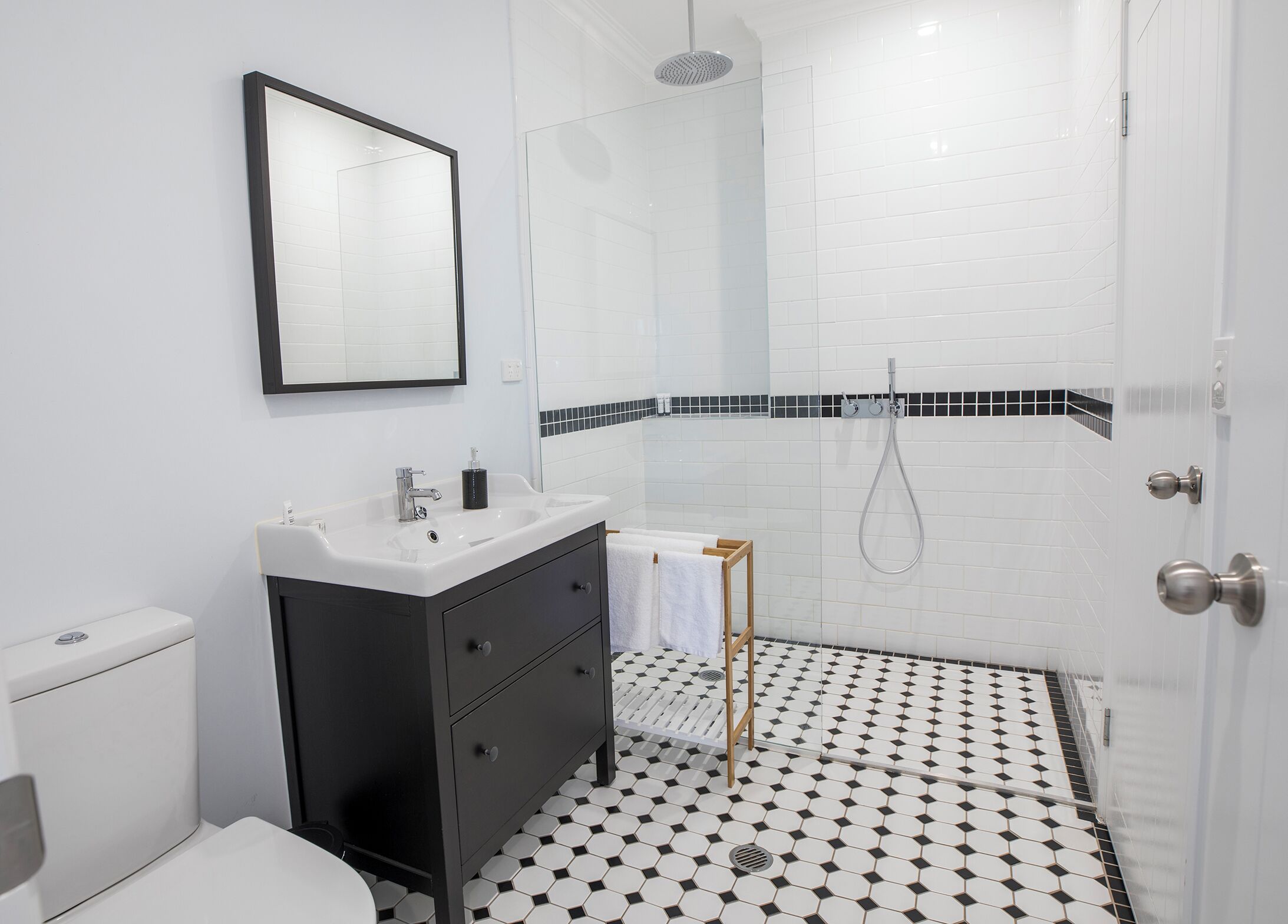 A modern bathroom with a white sink, black vanity, and a shower area.