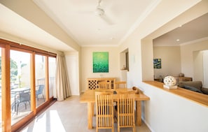 A spacious room with a wooden dining table and chairs, a ceiling fan, and a large window with curtains. - Kernow Charters Towers (Queenton)