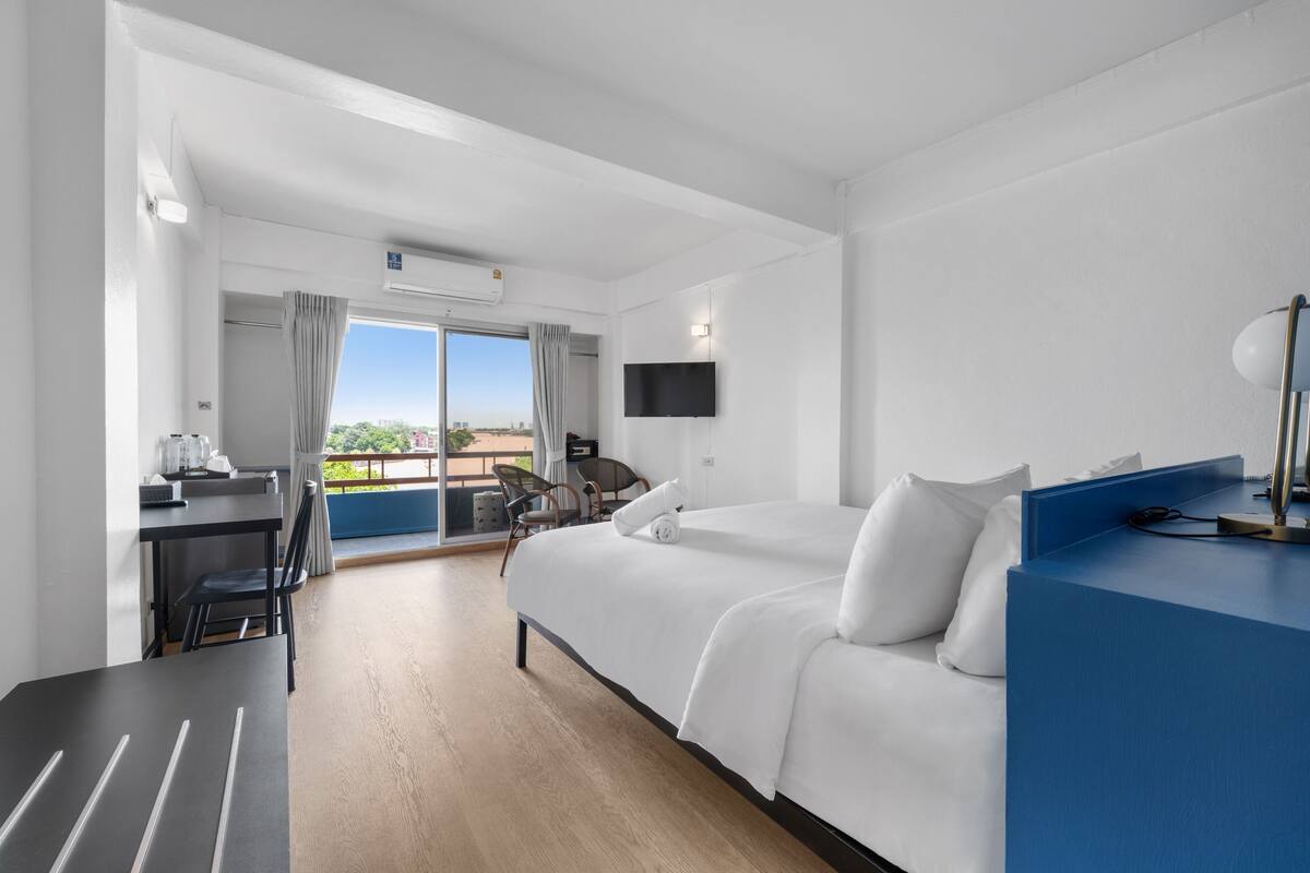 Ein Hotelzimmer mit Bett, Schreibtisch, Stuhl, Fernseher und einem Balkon mit Aussicht.