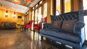 Un vestíbulo de hotel con un sofá azul, sillas rojas y suelo de baldosas.