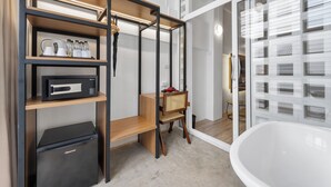 Un baño moderno con una bañera independiente, un tocador de madera con lavamanos y un estante con artículos de aseo.