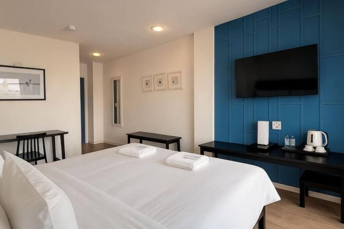 A hotel room with a bed, a desk, a flat-screen TV, and a coffee maker.