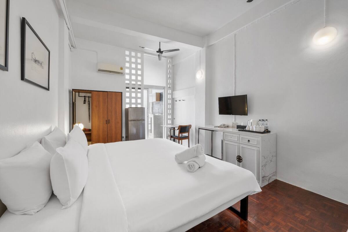 Ein Hotelzimmer mit einem großen Bett, einem Schreibtisch mit Stuhl, einem Fernseher und einer Minibar.