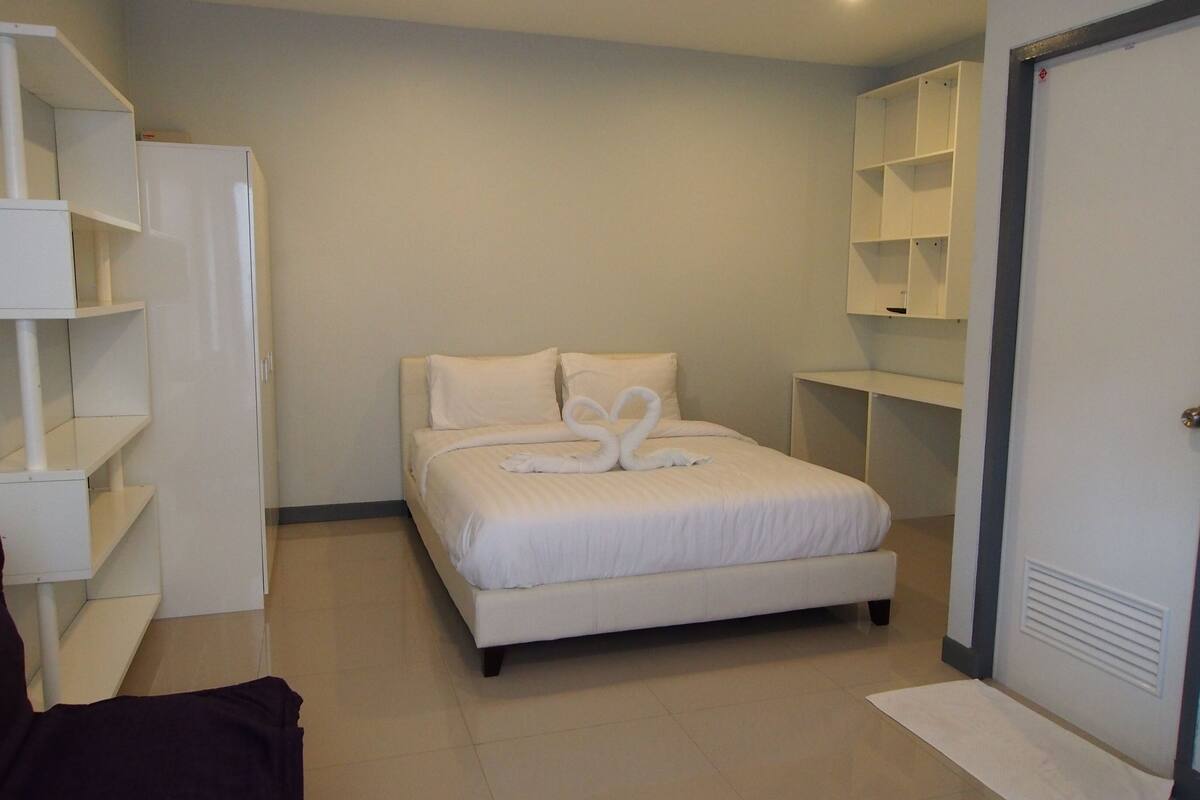 A neatly arranged bedroom with a bed, a wardrobe, and built-in shelving.