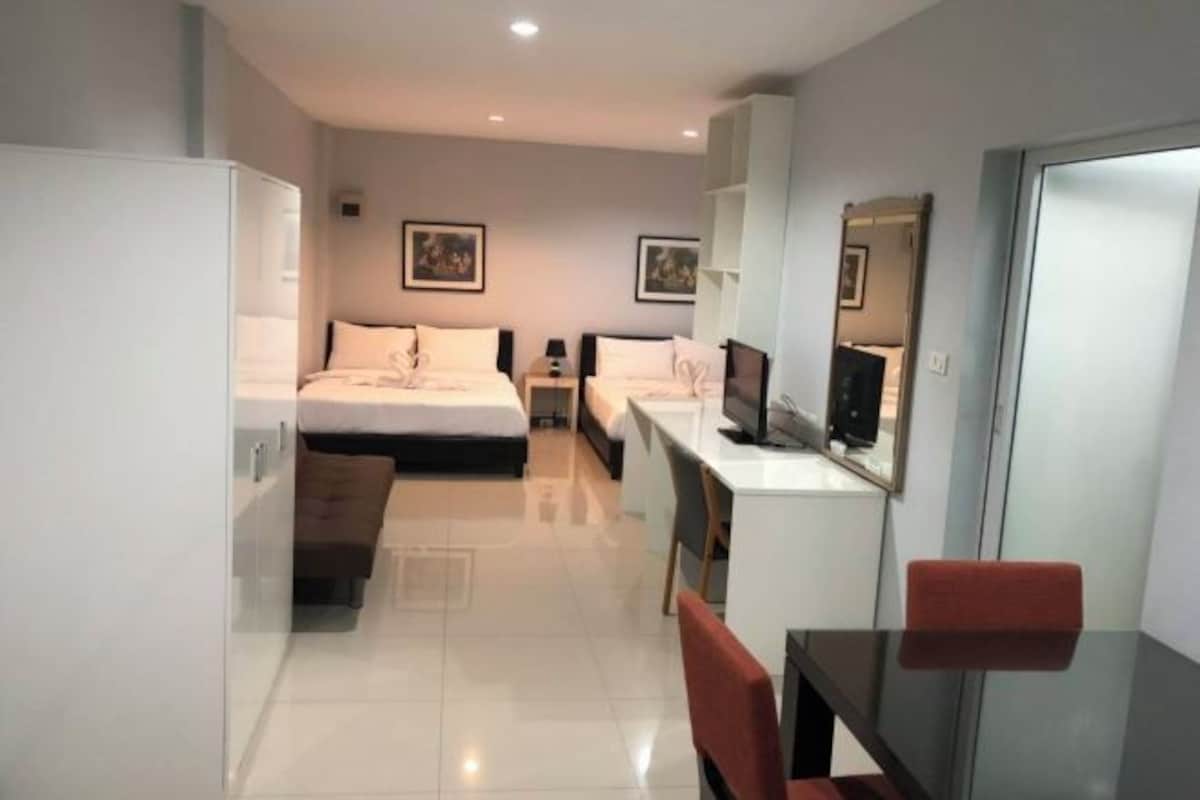 Una habitación de hotel moderna con una cama, un escritorio, una silla, un televisor y un armario.