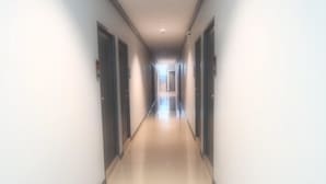 A long, narrow hallway with doors on both sides and a tiled floor. - I-Beyond Residence (Bangkok)