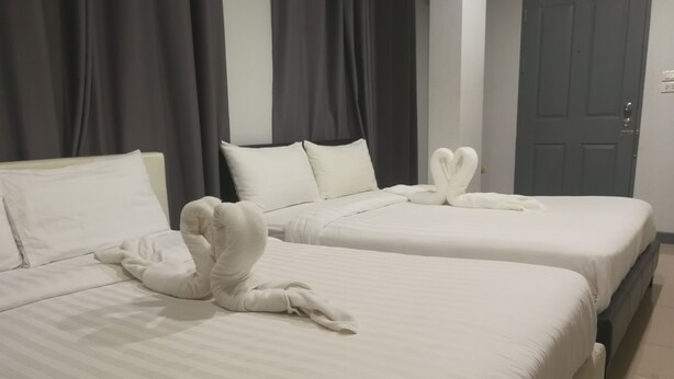 Two beds with white linens and pillows, a grey door, and dark curtains. - I-Beyond Residence (Bangkok)