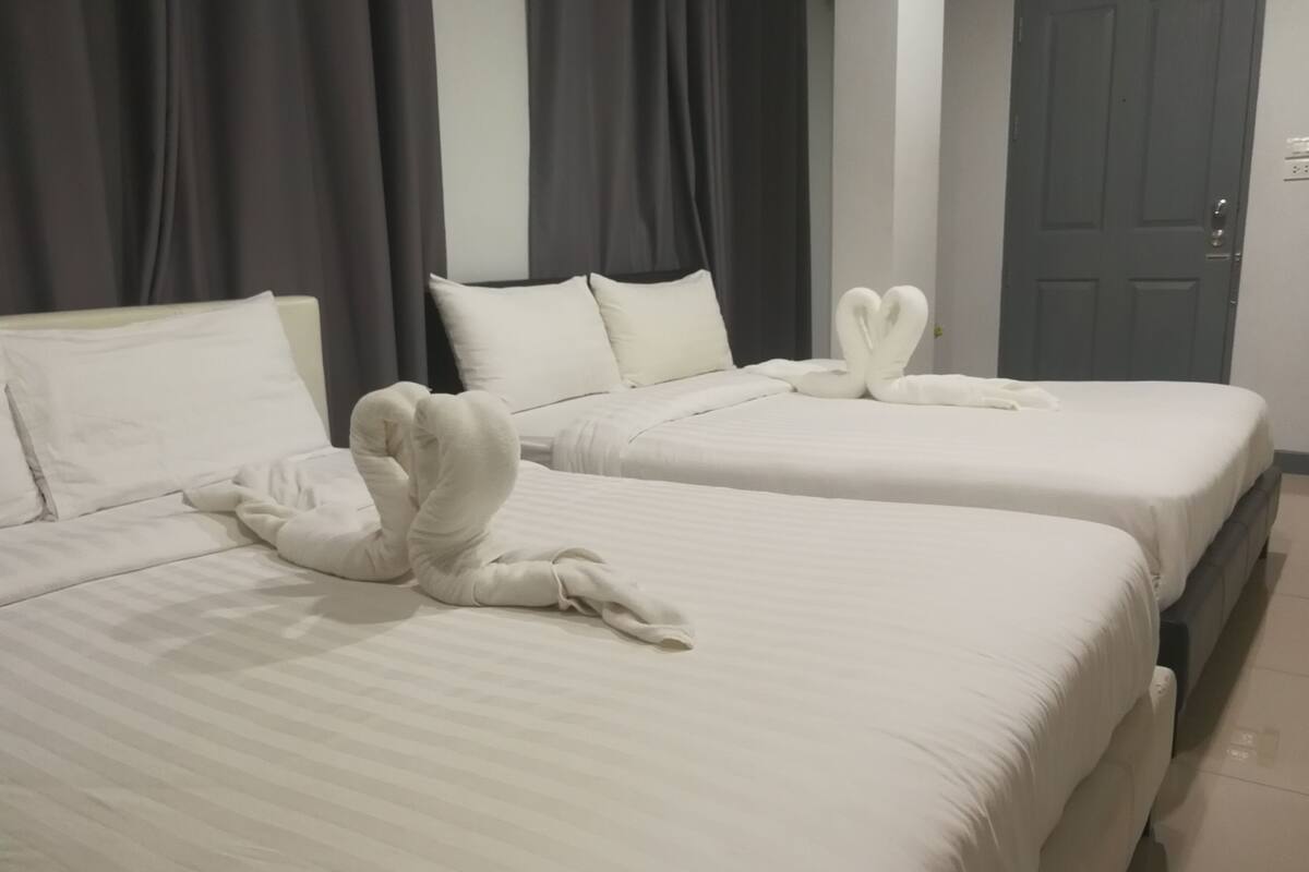 Two beds with white linens and pillows, a grey door, and dark curtains.
