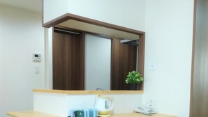A small kitchenette with a wooden countertop, a kettle, a coffee maker, and a bench. - Hotel Quartz Shin Osaka (Osaka)