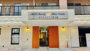 The entrance to Hotel Quarty Shin-Osaka with a modern design, featuring a signboard, a glass door, and a tiled pavement. - Hotel Quartz Shin Osaka (Osaka)