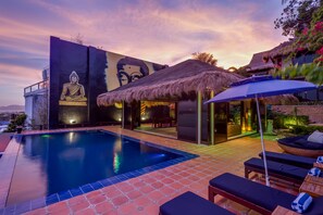 Una piscina al aire libre, sombrillas, sillones reclinables de piscina