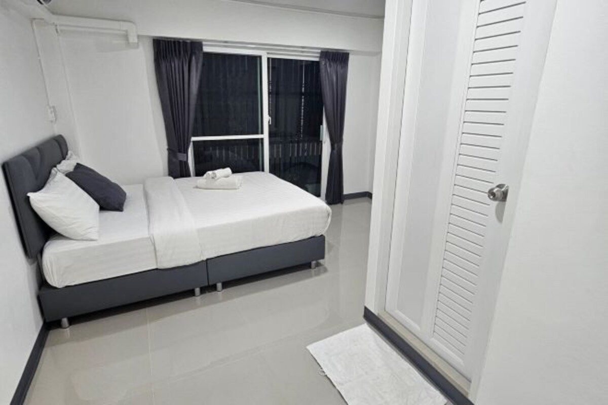 A bedroom with a bed, a window with curtains, and a door.