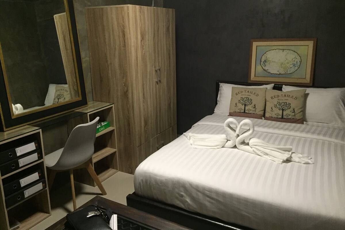 Une chambre d’hôtel comprenant un lit, un bureau, une chaise, une armoire et un miroir.