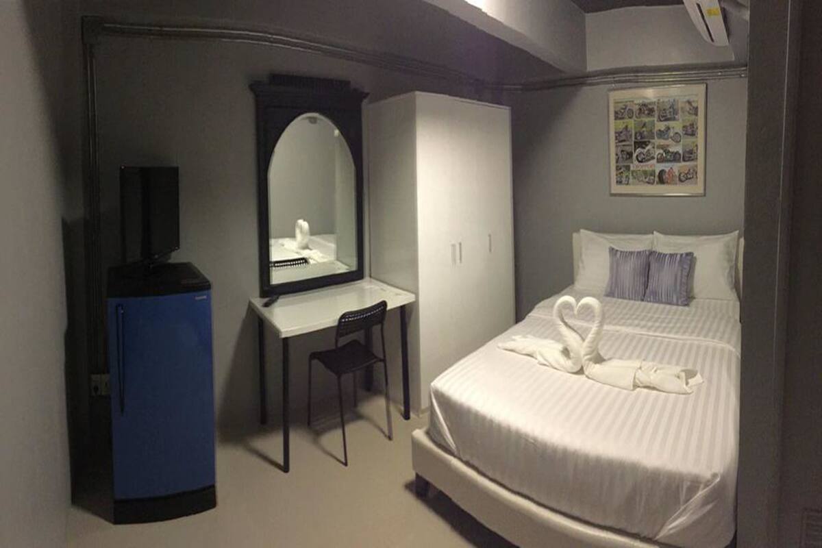 Une chambre d’hôtel comprenant un lit, un bureau, une chaise, une armoire et un miroir.