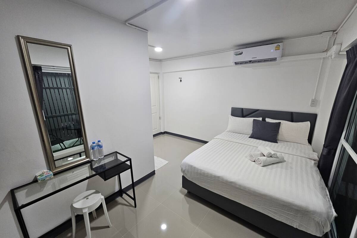 Une chambre d’hôtel équipée d’un lit, d’un bureau avec une chaise, d’un miroir et d’un appareil de climatisation.