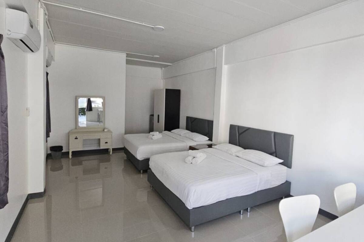 Une chambre d’hôtel moderne avec deux lits, une petite table de chevet, un miroir et un bureau avec des chaises.