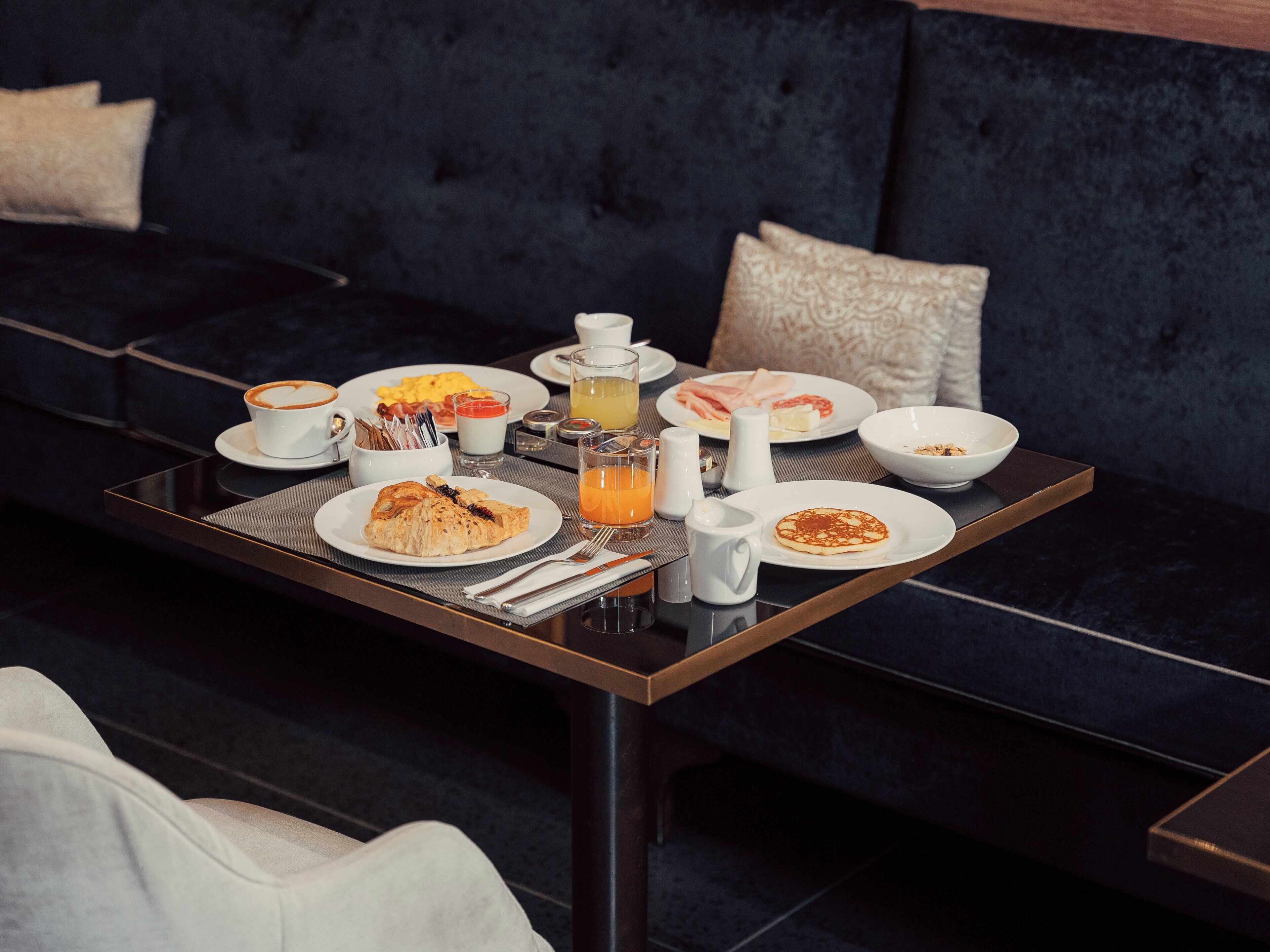 A breakfast table with plates of food, a coffee cup, and a juice glass.