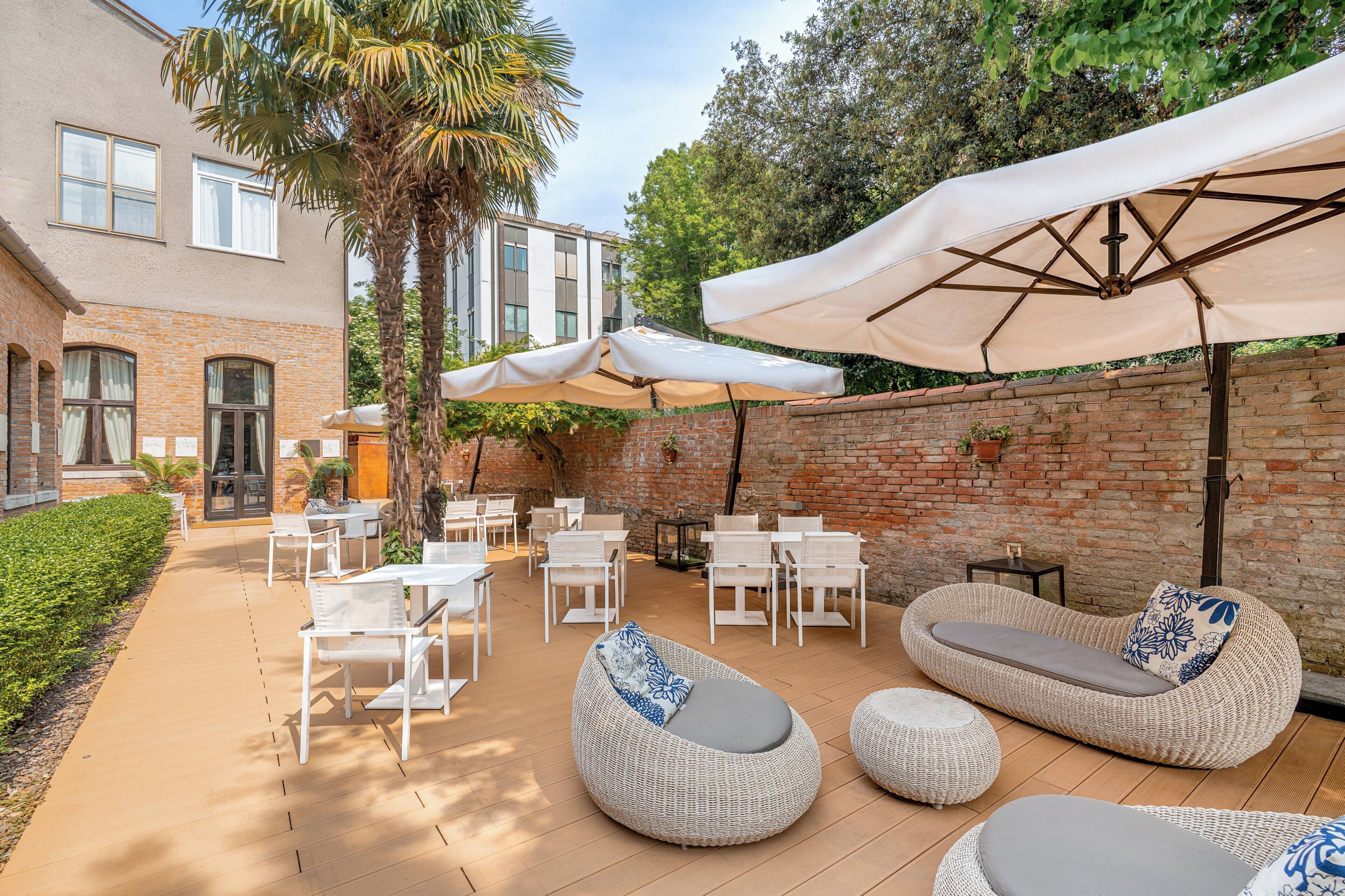 A patio with outdoor seating, umbrellas, and a brick wall.