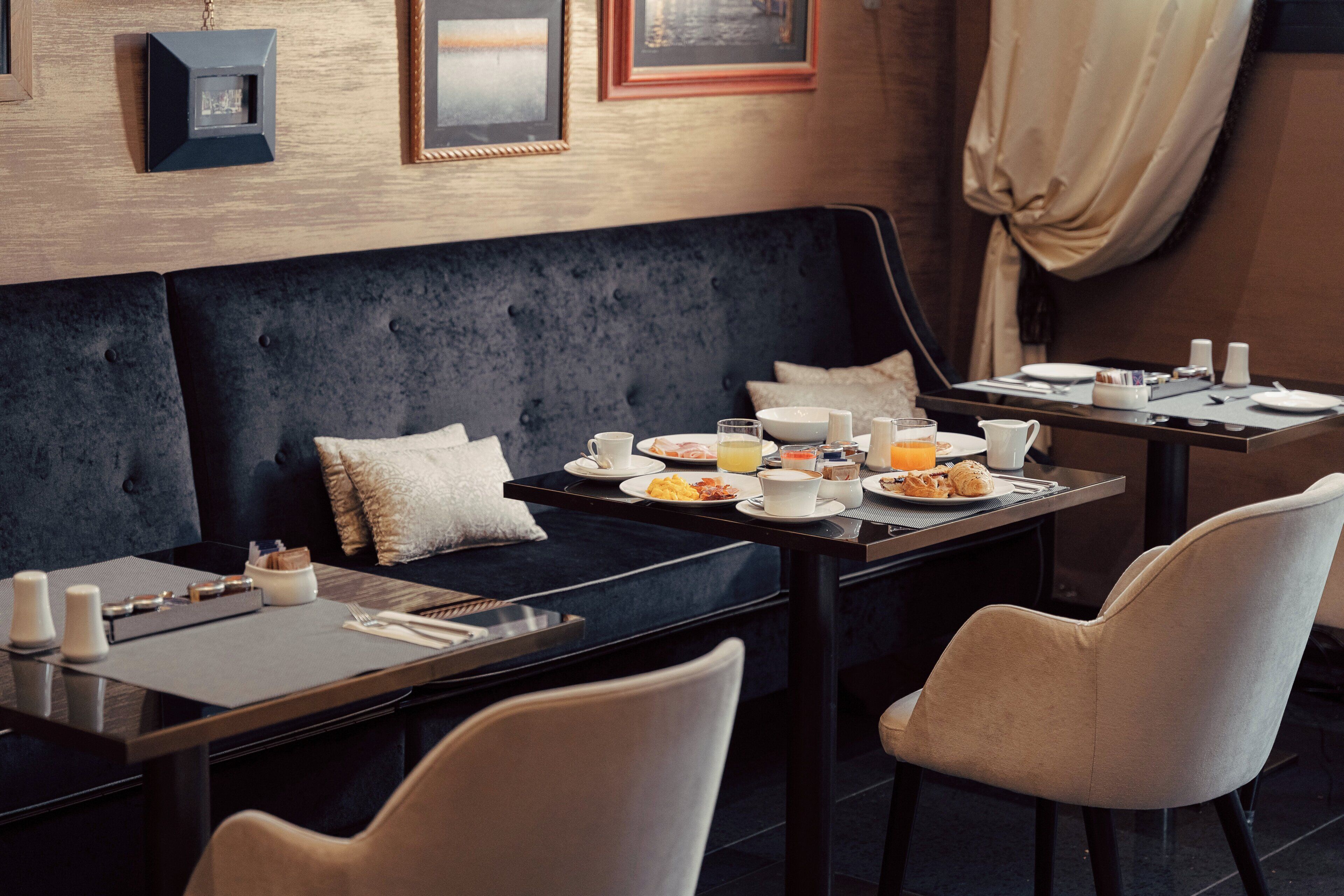 A dining area with a dark upholstered sofa, a table set with plates, glasses, and a tray.