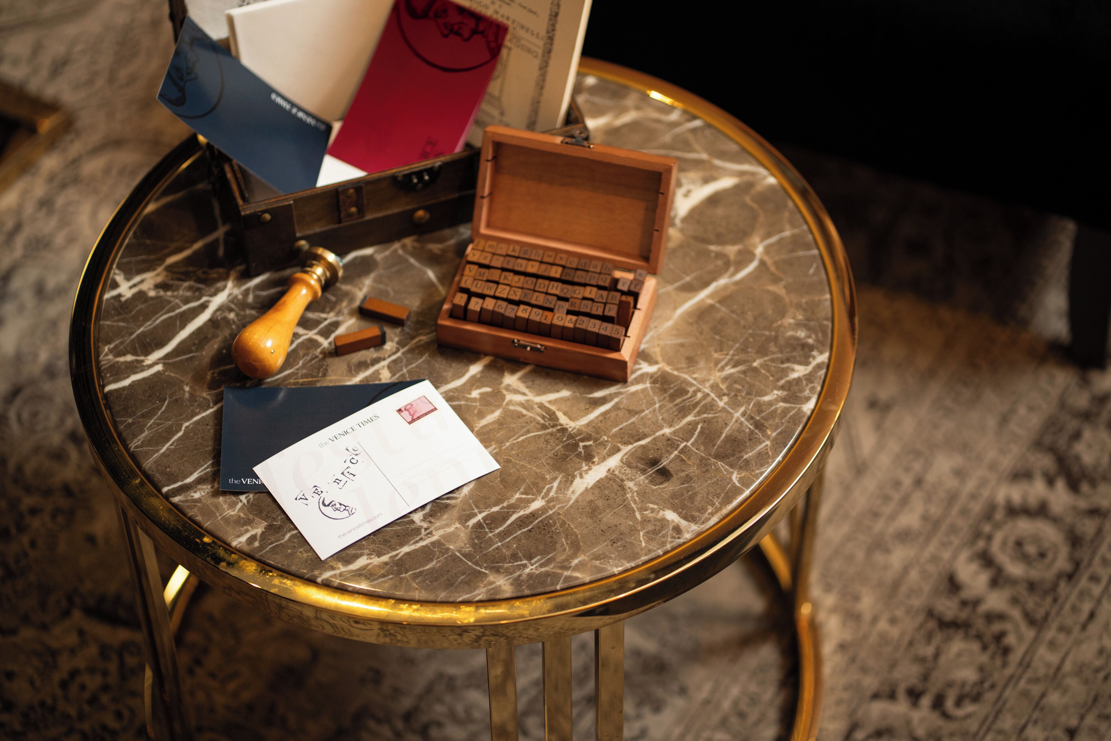 A small round table with a marble top, a wooden box, a wooden hammer, and a few papers.