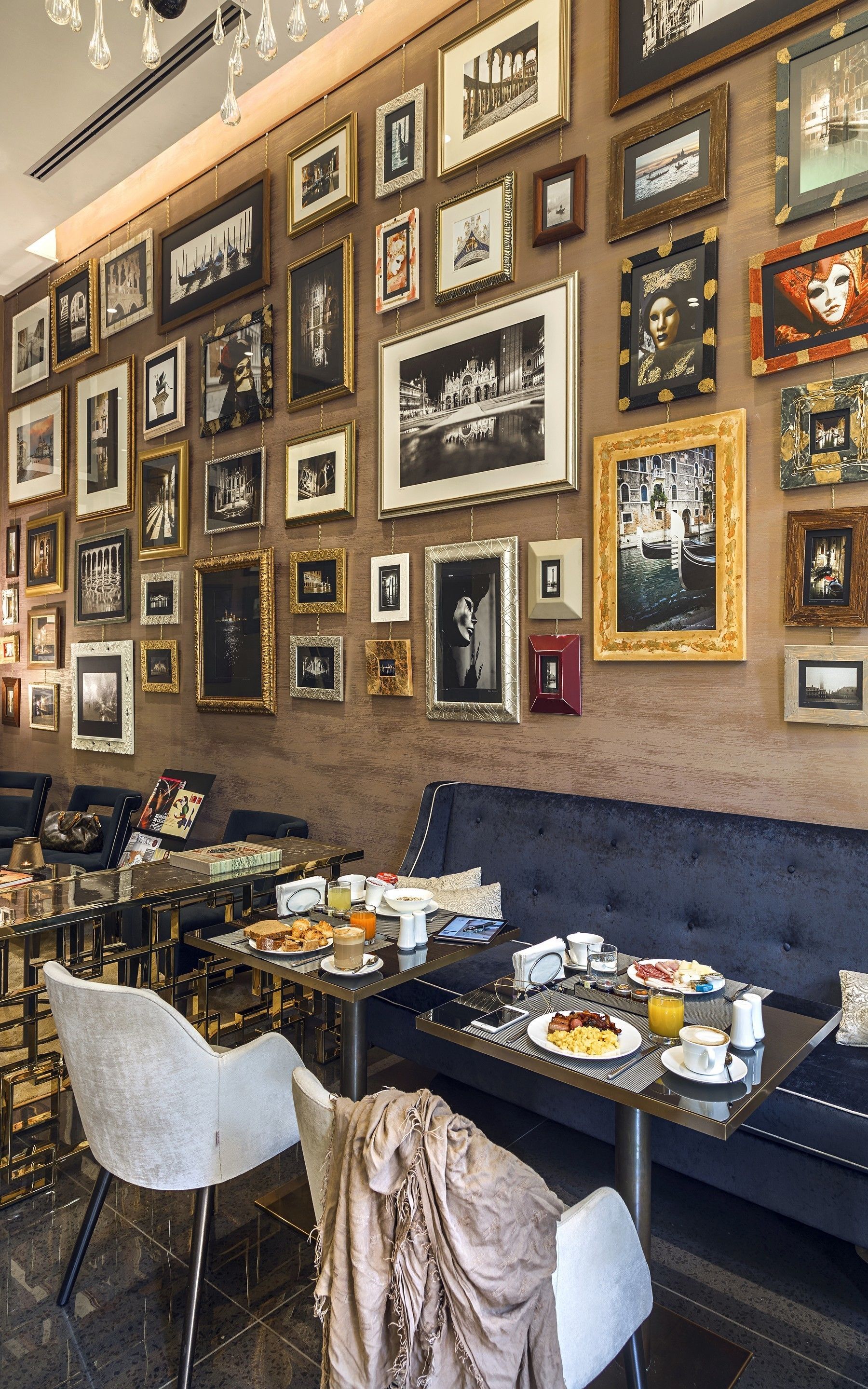 A dining area with a variety of framed pictures on the wall, a sofa, and a table set with breakfast.