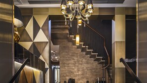 A modern lobby with a grand staircase, a chandelier, and a bench. - The Venice Times Hotel, Vignette Collection by IHG (Venice)