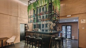 A bar area with a central bar counter, multiple stools, and a shelving unit with bottles. - The Venice Times Hotel, Vignette Collection by IHG (Venice)