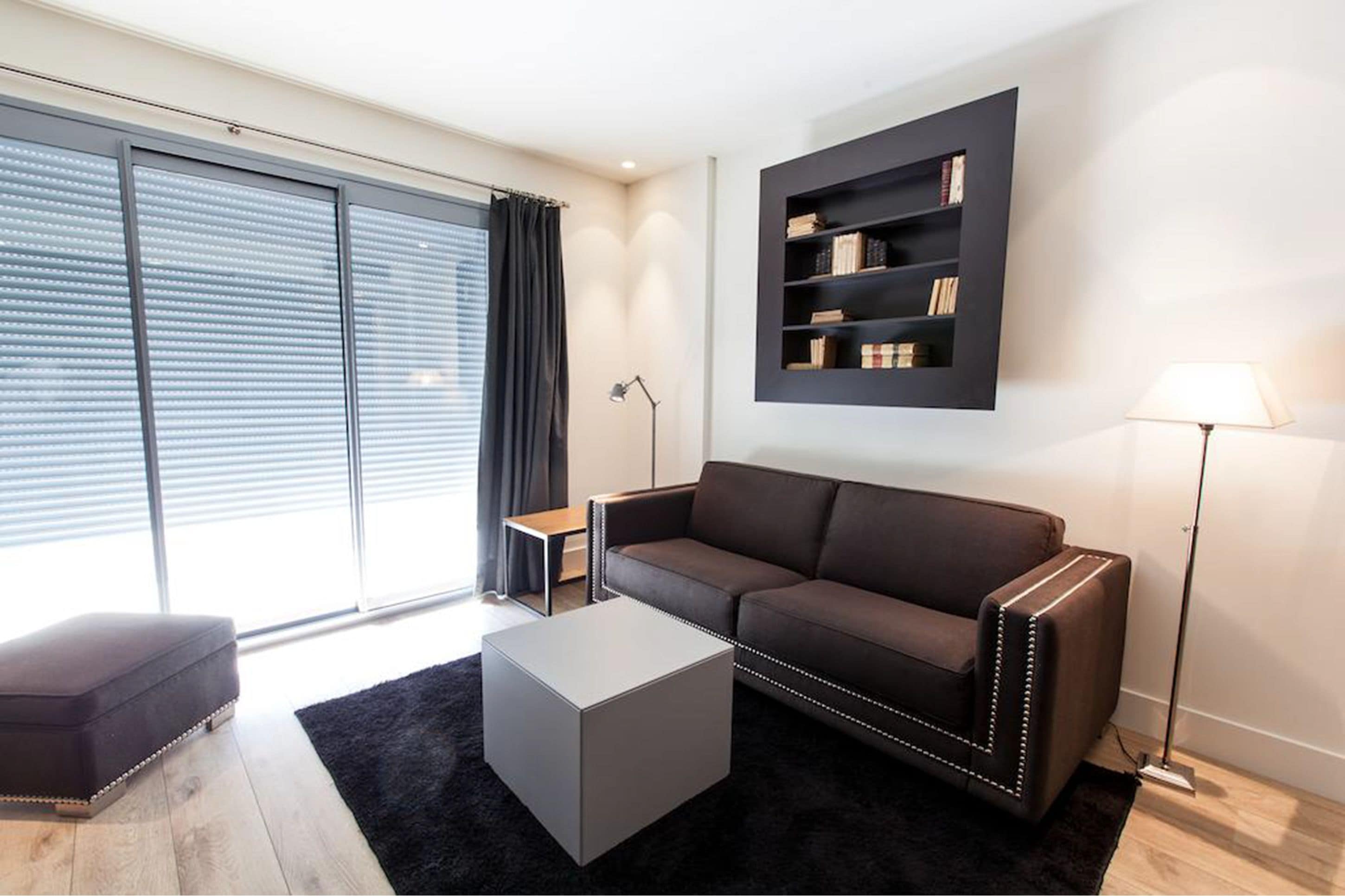 A modern living room with a sofa, a coffee table, a bookshelf, and a floor lamp.