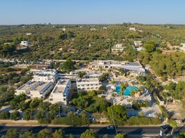 Vista aérea de un complejo turístico con varias construcciones, una piscina y vegetación circundante.
