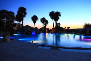 Un área de piscina con palmeras y un sendero de piedra.