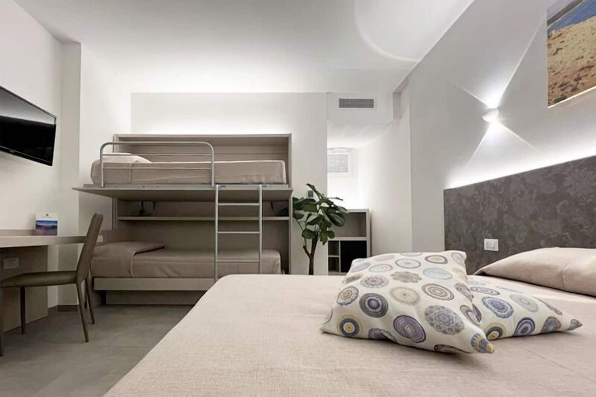 A bunk bed room with a desk, chair, and a plant.