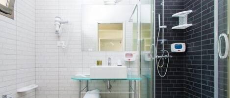 Un baño moderno con ducha de vidrio, lavamanos blanco y un bidé.