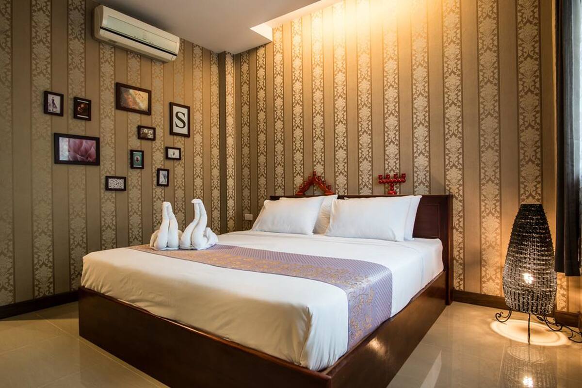 Una habitación de hotel con una cama grande, un aire acondicionado de pared y una lámpara de pie decorativa.