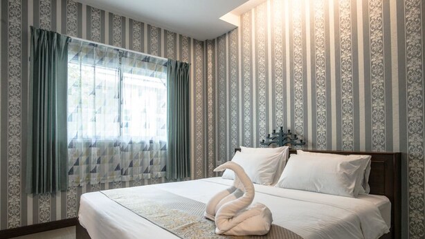 A hotel room with a large bed, striped wallpaper, and a window with curtains. - Sunday J Resort & Restaurant (Chonburi)