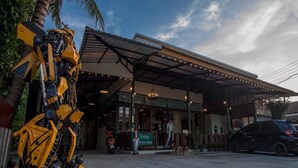 A building with a covered entrance, a sign indicating it's open, and a parked car. - Sunday J Resort & Restaurant (Chonburi)