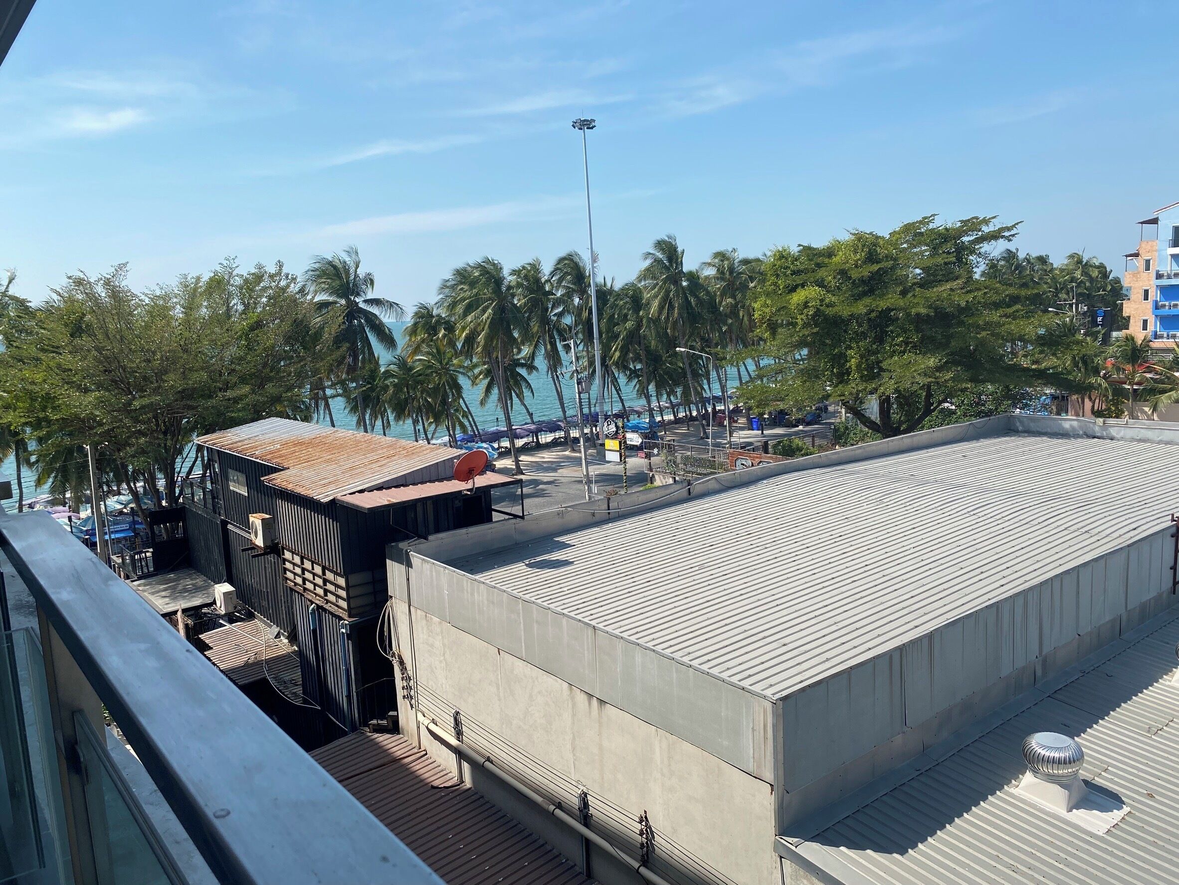 A view of a building with a flat roof, a satellite dish, and a small structure with a corrugated metal roof.