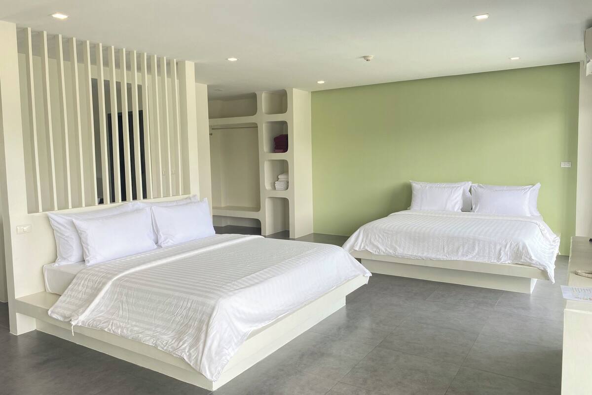 Una habitación de hotel moderna con dos camas, un vestidor y una pared de acento verde.