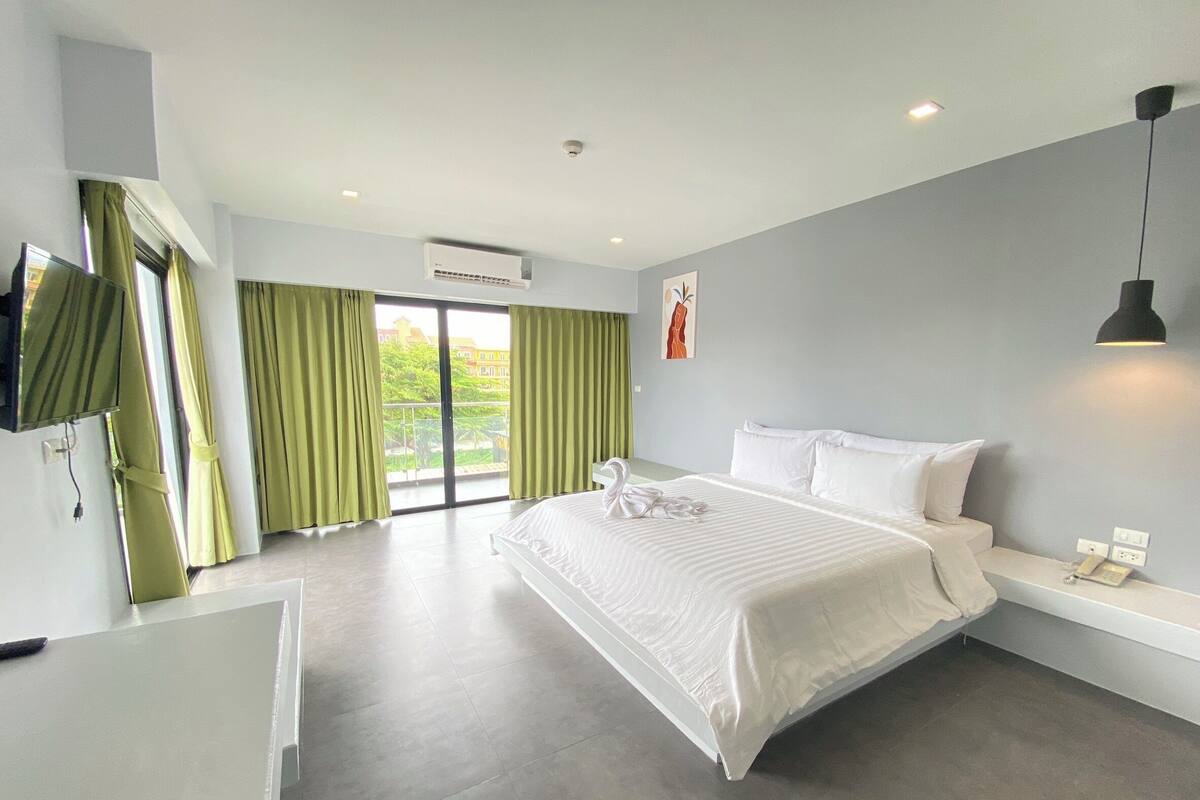 Una habitación de hotel moderna con una cama grande, un escritorio y vistas al exterior.