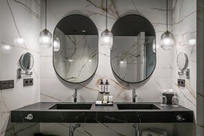 A bathroom with two sinks, marble walls, and two round mirrors. - Hotel Barcelona Catedral (Barcelona)
