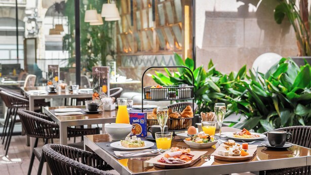 A breakfast setting with a variety of dishes, including eggs, toast, and pastries, along with beverages like orange juice and coffee. - Hotel Barcelona Catedral (Barcelona)