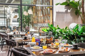 A breakfast setting with a variety of dishes, including eggs, toast, and pastries, along with beverages like orange juice and coffee. - Hotel Barcelona Catedral (Barcelona)