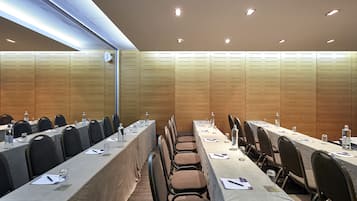 A conference room with long tables, chairs, and a wooden panel wall.