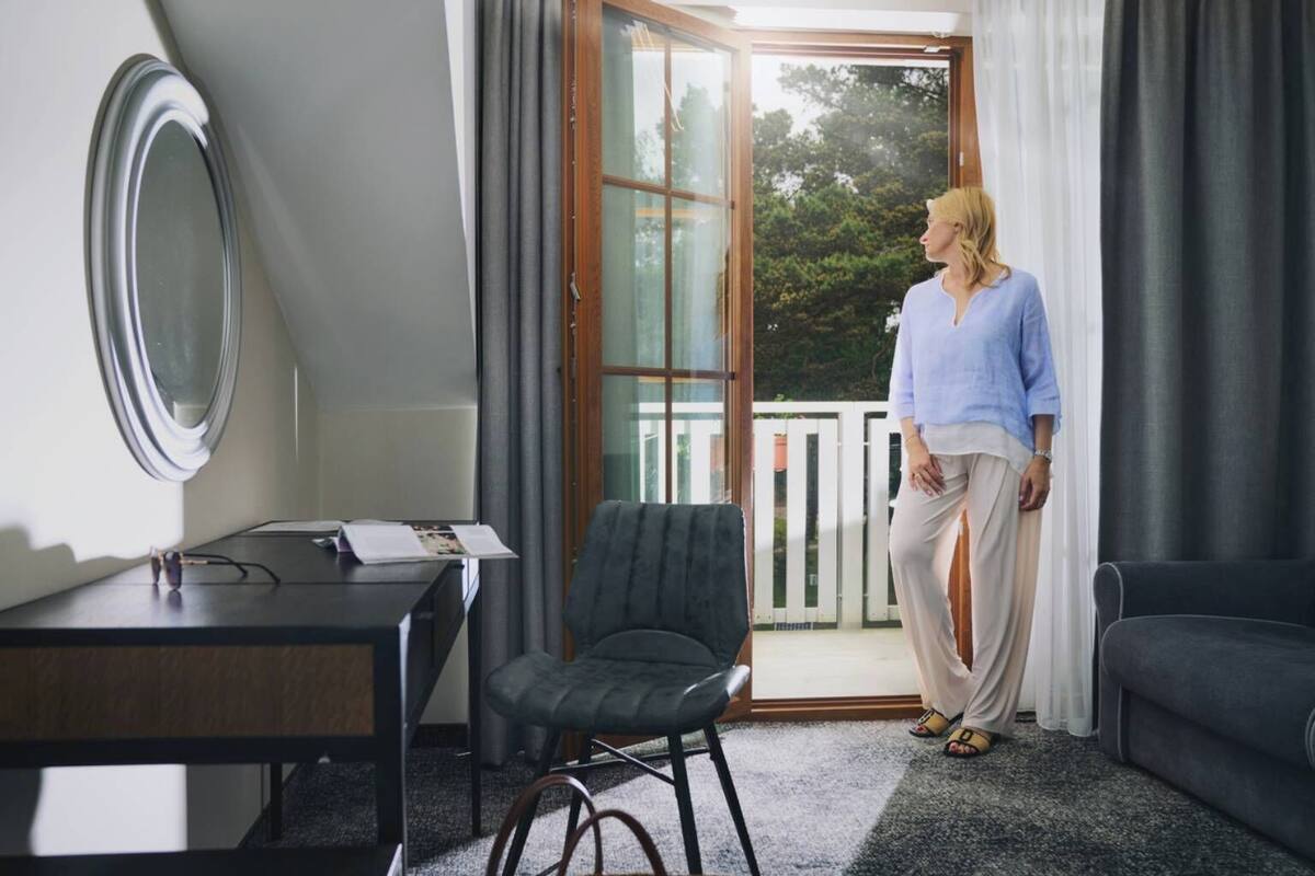 A room with a desk, chair, and a large window with curtains.