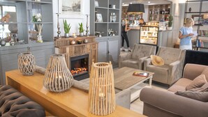 Una sala de estar moderna con chimenea, sofás y una mesa de centro. Hay elementos decorativos en estanterías y una zona de bar al fondo.