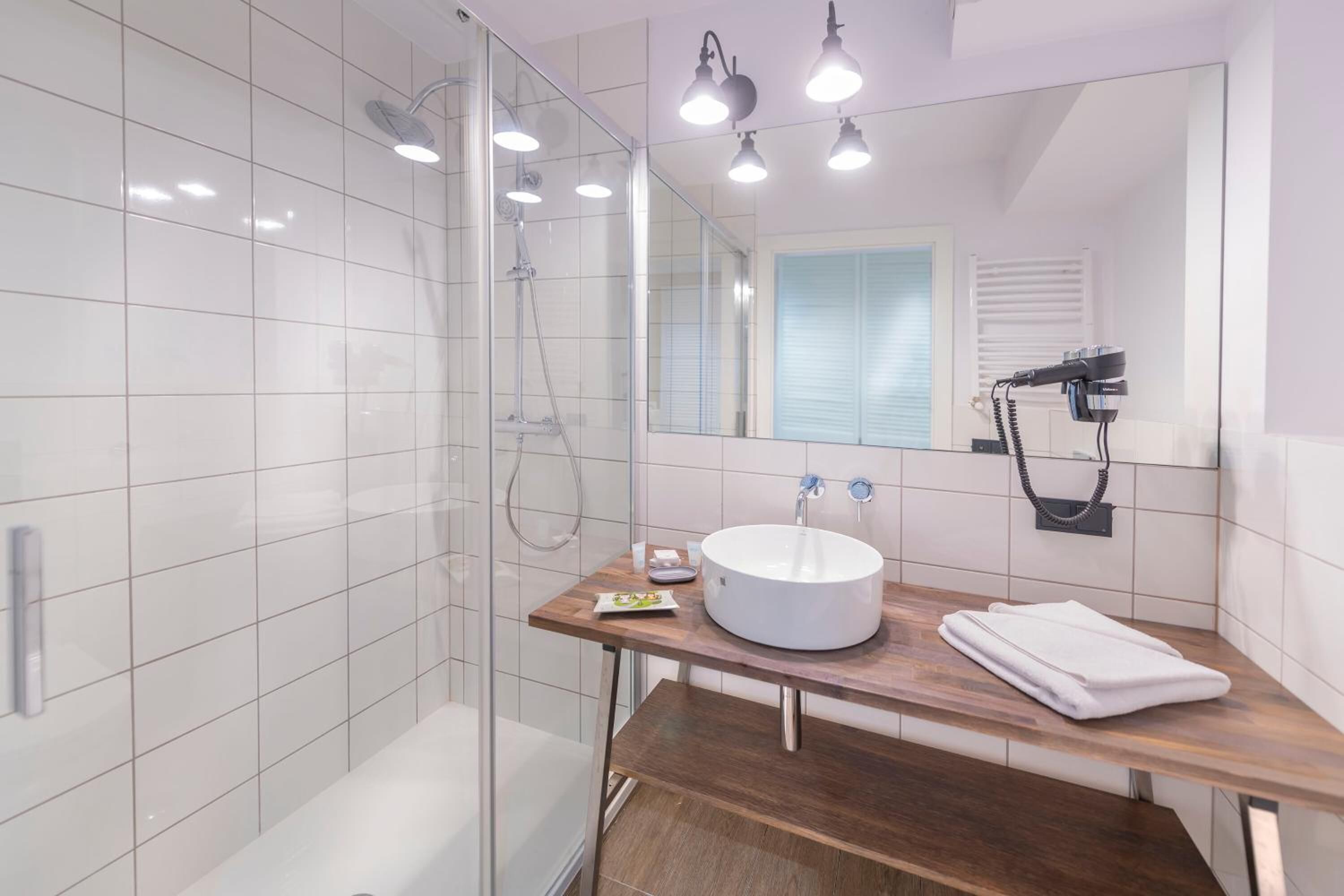 A modern bathroom with a glass shower enclosure, a white sink, and a wooden vanity.